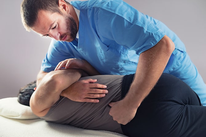 chiropractor adjusting male patients lower back