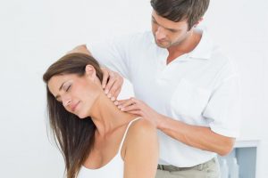 chiropractor massaging female patients neck