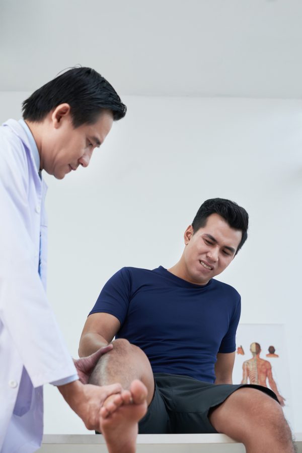 chiropractor examining patients knee